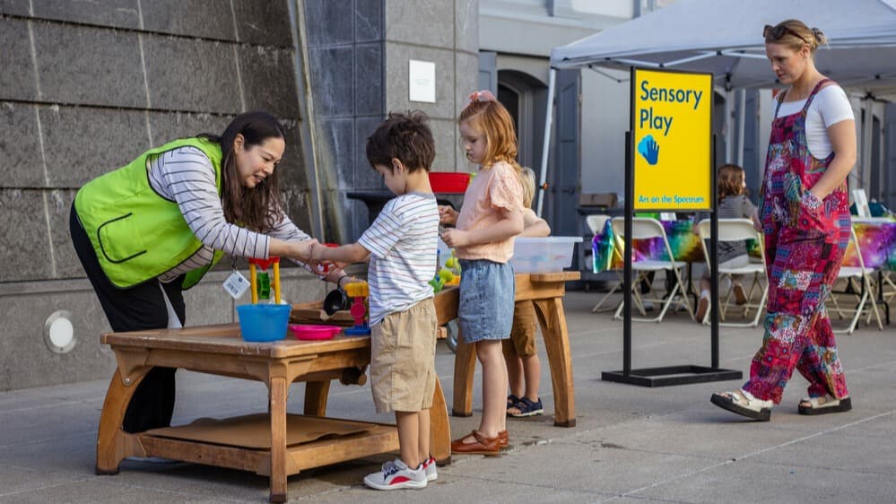 Children explore a sensory table at the Crocker's Art on the Spectrum.